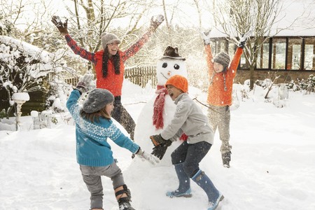 Mother And Children Building Snowman In Gardenの写真素材