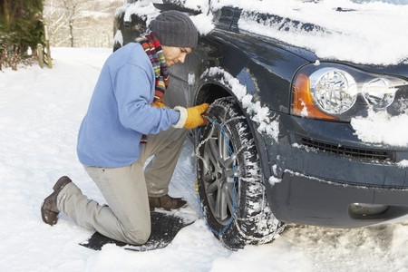 Man Putting Snow Chains Onto Tyre Of Carの写真素材