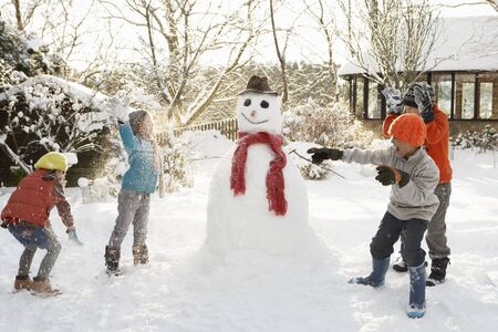 Mother And Children Building Snowman In Gardenの写真素材