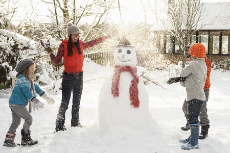 Mother And Children Building Snowman In Gardenの写真素材