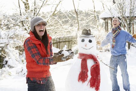 Young Couple Having Snowball Fight In Gardenの写真素材