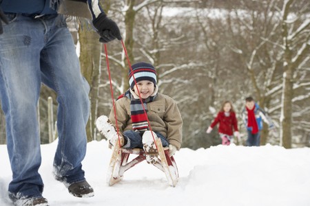 Father Pulling Children On Sledge Through Winter Landscapeの写真素材