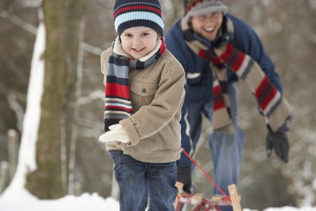Children Pulling Sledge Through Winter Landscapeの写真素材