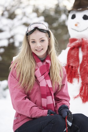 Teenage Girl With Sledge Next To Snowmanの写真素材