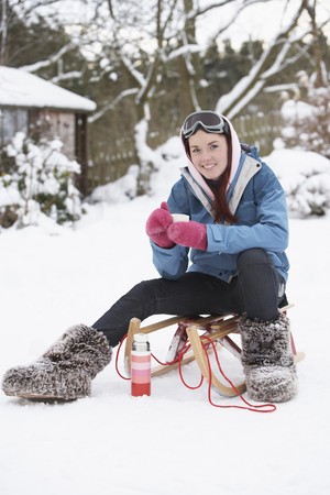 Teenage Girl With Sledge Next To Snowman With Flask And Hot Drinkの写真素材