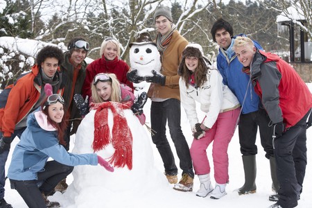 Group Of Teenage Friends Building Snowman In Gardenの写真素材