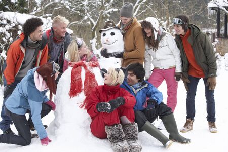 Group Of Teenage Friends Building Snowman In Gardenの写真素材