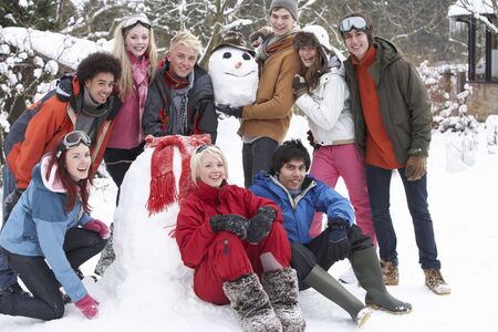 Group Of Teenage Friends Building Snowman In Gardenの写真素材