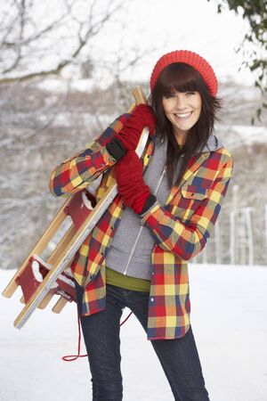 Woman Holding Sledge In Snowy Landscapeの写真素材