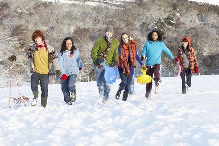 Group Of Teenage Friends Sledging In Snowy Landscapeの写真素材