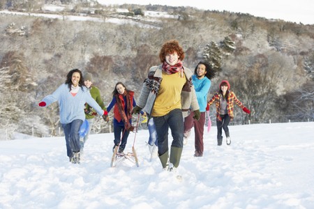 Group Of Teenage Friends Sledging In Snowy Landscapeの写真素材