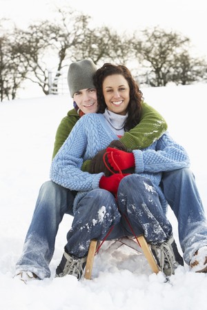 Couple Sledging Through Snowy Woodlandの写真素材