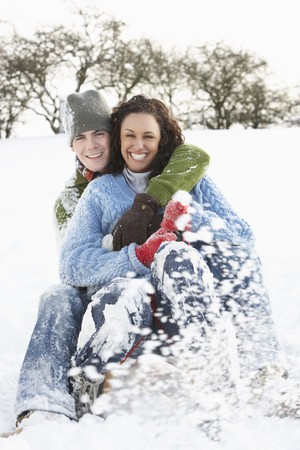 Couple Sledging Through Snowy Woodlandの写真素材