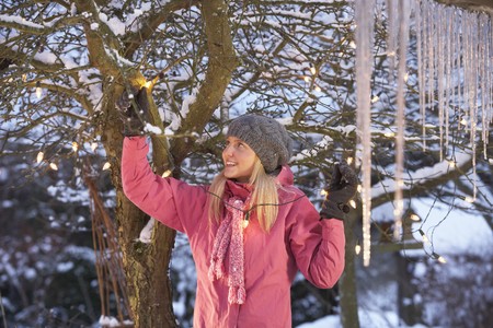 Teenage Girl Hanging Fairy Lights In Tree With Icicles In Foregroundの写真素材