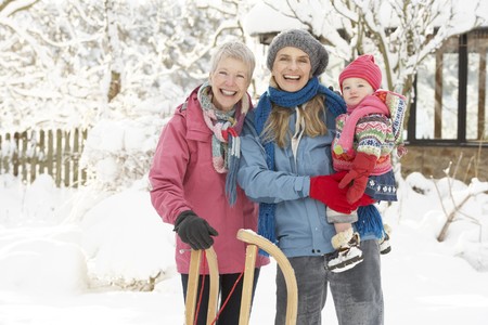 Young Girl With Grandmother And Mother Holding Sledge In Gardenの写真素材