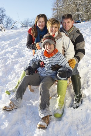 Family Enjoying Sledging Down Snowy Hillの写真素材