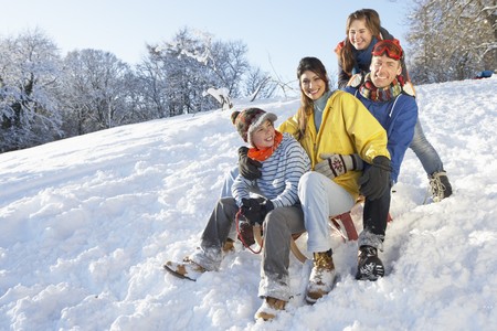Family Enjoying Sledging Down Snowy Hillの写真素材