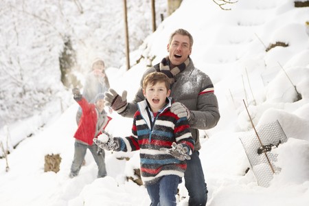 Family Having Snowball Fight In Snowy Landscapeの写真素材