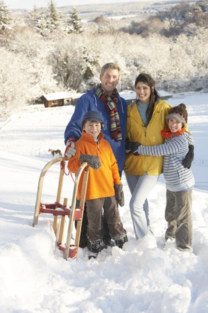 Young Family Standing In Snowy Landscape Holding Sledgeの写真素材