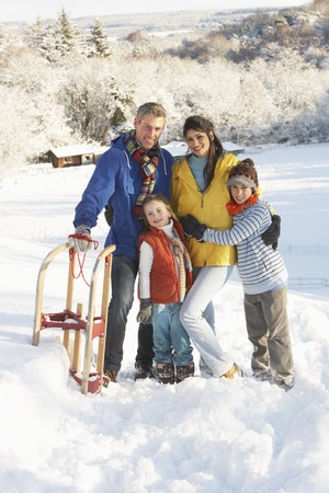 Young Family Standing In Snowy Landscape Holding Sledgeの写真素材