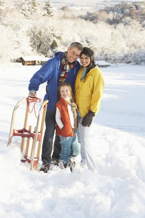 Young Family Standing In Snowy Landscape Holding Sledgeの写真素材