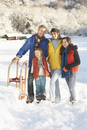 Young Family Standing In Snowy Landscape Holding Sledgeの写真素材