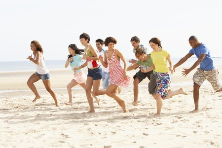 Group Of Friends Running Along Beach Togetherの写真素材