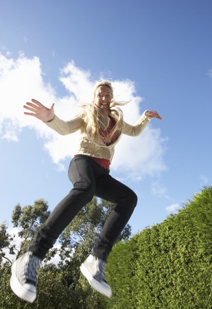 Young Woman Jumping On Trampoline Caught In Mid Airの写真素材