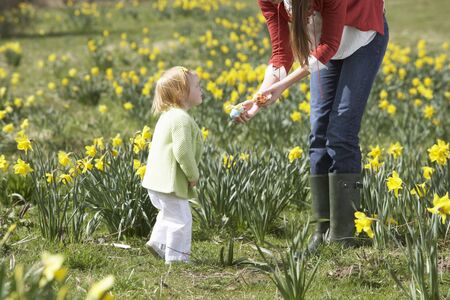 Mother And Daughter In Daffodil Field With Decorated Easter Eggsの写真素材