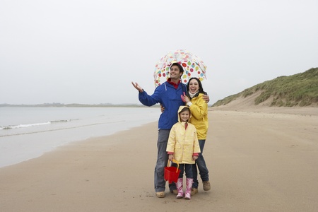 Happy family on beach with umbrellaの写真素材