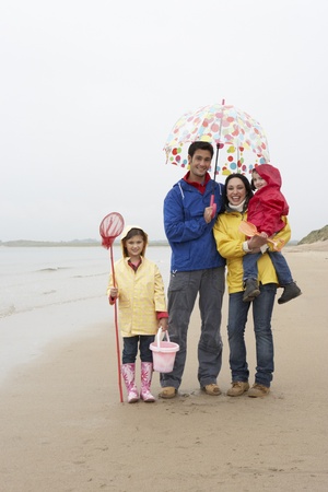 Happy family on beach with umbrellaの写真素材