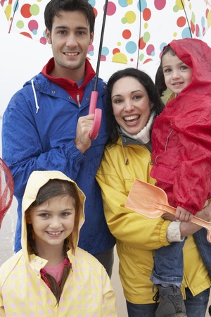 Happy family on beach with umbrellaの写真素材