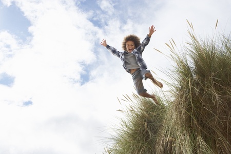 Boy jumping over duneの写真素材