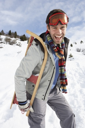 Young Man Carrying Sled In Alpine Landscapeの写真素材