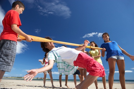 Teenagers doing limbo dance on beachの写真素材