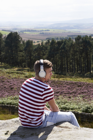Young Man Listening To Music In Countryside On Headphonesの写真素材