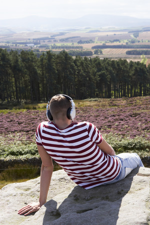 Young Man Listening To Music In Countryside On Headphonesの写真素材