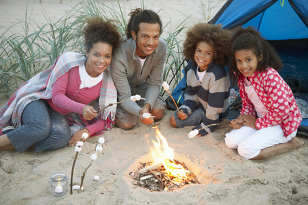 Family Camping On Beach And Toasting Marshmallowsの写真素材