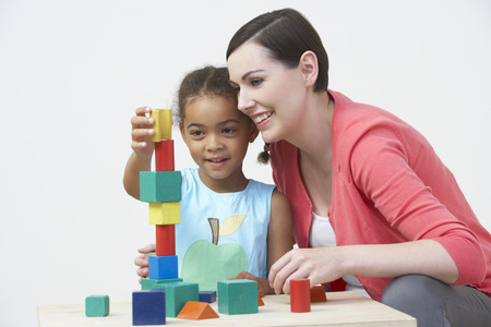 Teacher And Pre-School Pupil Playing With Wooden Blocksの写真素材