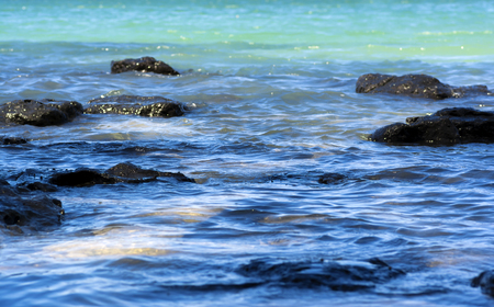 Turquoise ocean waves splashing on rocksの写真素材