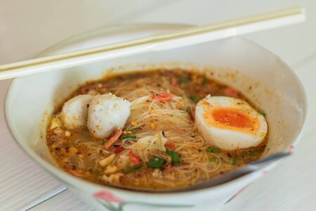 Thai noodle with (egg, pork and ball pork) tomyum spicy soup, in a bowlの写真素材