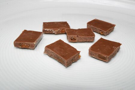 Pieces of a bar of chocolate on white dishの写真素材