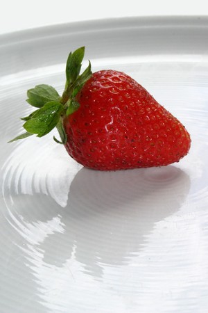 An isolated red strawberry on white dishの写真素材