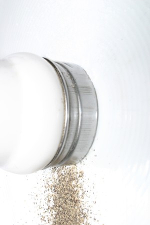 Pepper shaker, on white background with pepper trickling outの写真素材