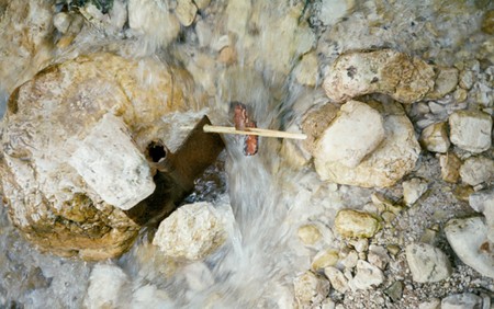 Wooden water wheel running between two stones of a mountain brookの写真素材
