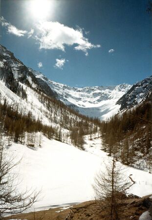 view into a mountain valley with snow and the sunの写真素材