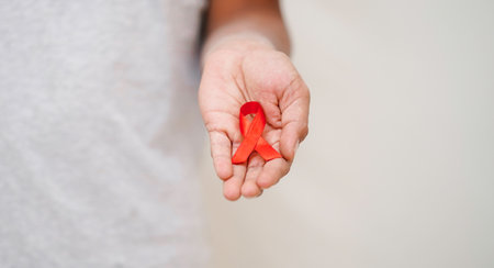 female hand with red aids awareness ribbon, HIV AIDS Badge to spread HIV AIDS Awareness, Healthcare,...