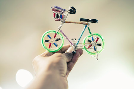 Man holding green color cycle toy showpiece handmade with aluminium children toys in green color selling in market, fair, mall, or storeの写真素材