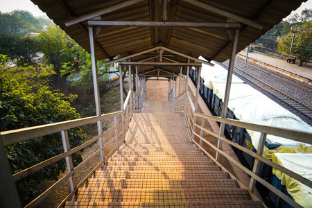 Railway station foot over staircase goes to Foot over bridge, inside view of station corridor, staircase of a foot over bridge at a rural railway station , and sun ray coming from left sideの写真素材