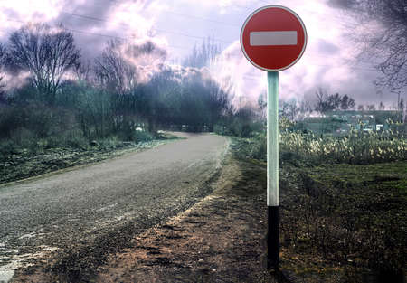 The road sign "Entry is prohibited". A lonely crooked road.の写真素材